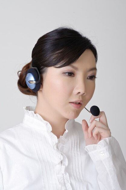 Asian business woman working, closeup portrait on gray wall.