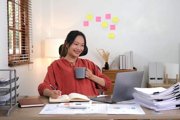 Азиатская деловая женщина, работающая в кафе-кафе с бумажной работой на ноутбуке