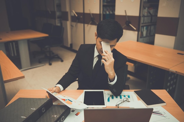 Asian businessman in black suit think idea for work at officehe work overtime alone in a companydark tonethailand people