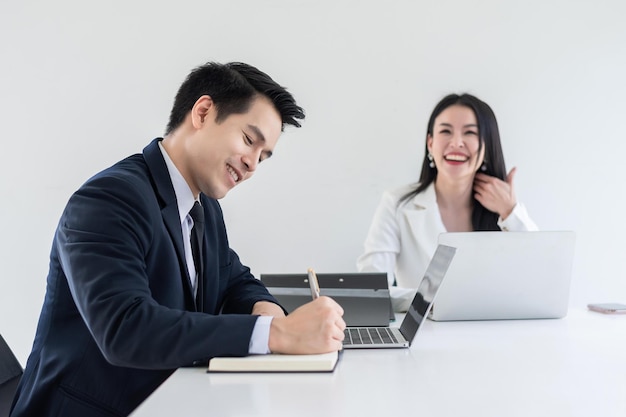 Foto l'uomo d'affari e la donna d'affari asiatici si incontrano felicemente e utilizzano un tablet e prendono appunti in ufficio