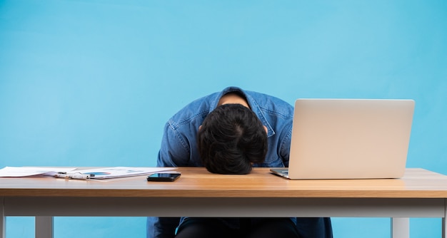 Asian businessman dropped his head on the table because of the pressure at work