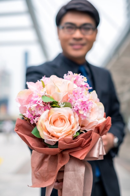 おめでとうのためにバラの花束を保持しているアジアの実業家