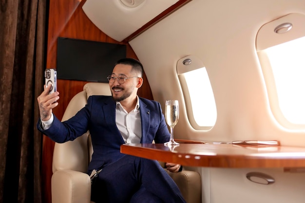 asian businessman is sitting in private luxury jet and communicate via smartphone