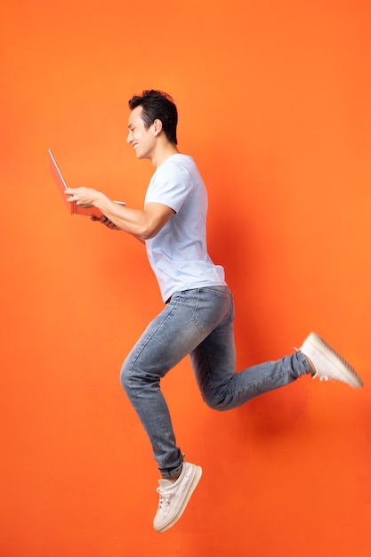 Asian businessman jumping and holding laptop