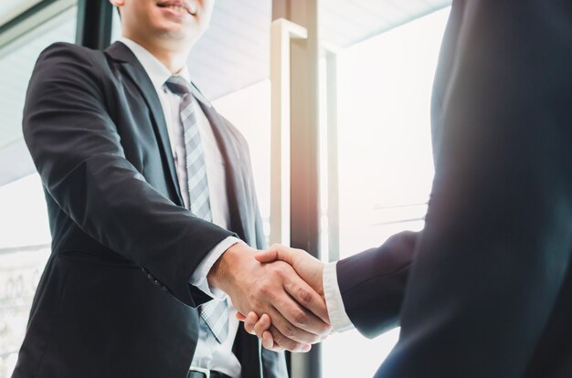 Photo asian businessman making handshake with a businesswoman - greeting and dealing concepts