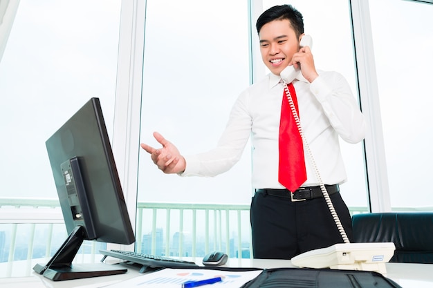 Asian businessman  on phone working in office