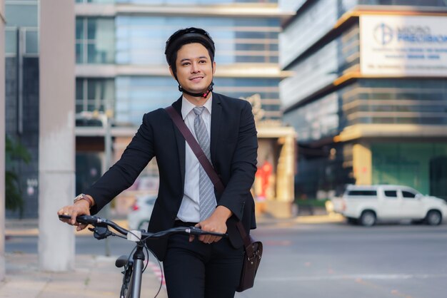 自宅から自転車を押すアジアのビジネスマン