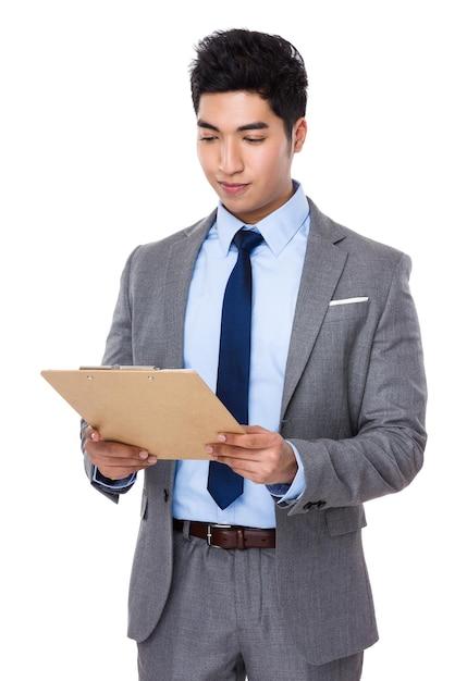 アジア系のビジネスマンがクリップボードのレポートを読む