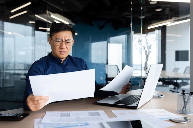 Asian businessman not satisfied with achievement results boss looking at documents and upset man in