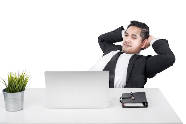 机の上のラップトップでリラックスしながら座っているアジア系のビジネスマン