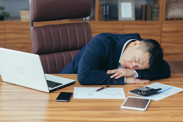 Asian businessman sleeping tired lying on the table man at work