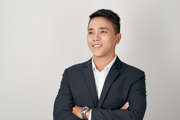 Asian businessman standing with his arms crossed and smiling on a white background