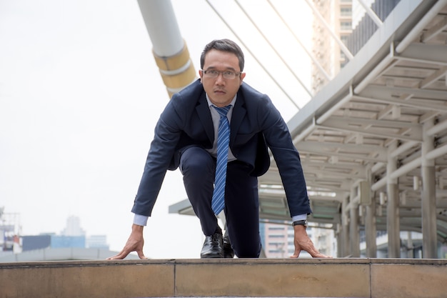 Asian Businessman in suit preparing to run,getting ready to run the race