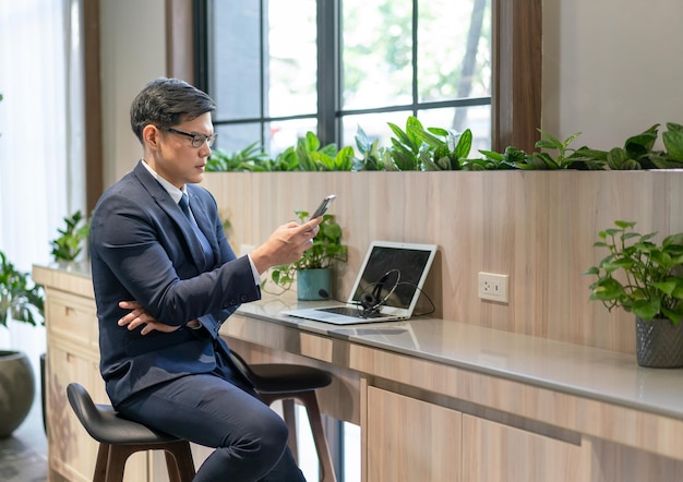 Uomo d'affari asiatico in giacca e cravatta che utilizza lo smartphone dopo aver incontrato la videoconferenza sul posto di lavoro all'esterno