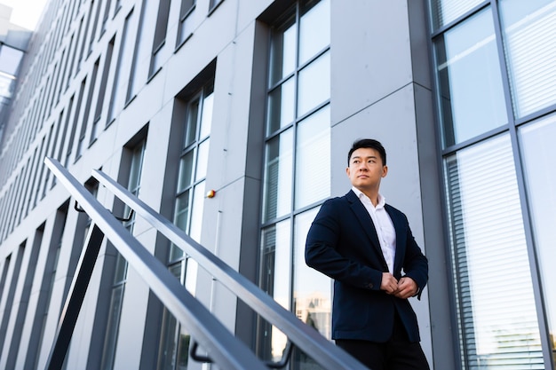 Asian businessman walks up the stairs of the office center, man\
hurries to a business meeting in a suit