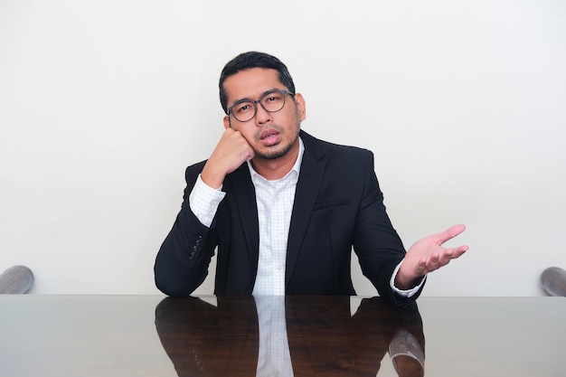 Asian businessman wearing black suit showing hopeless expression