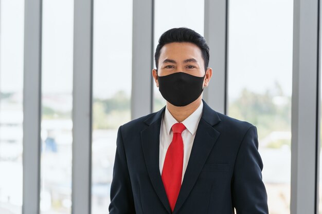 사진 사무실에서 코로나 바이러스 예방에 마스크를 쓰고 아시아 사업가. 개념 건강 관리