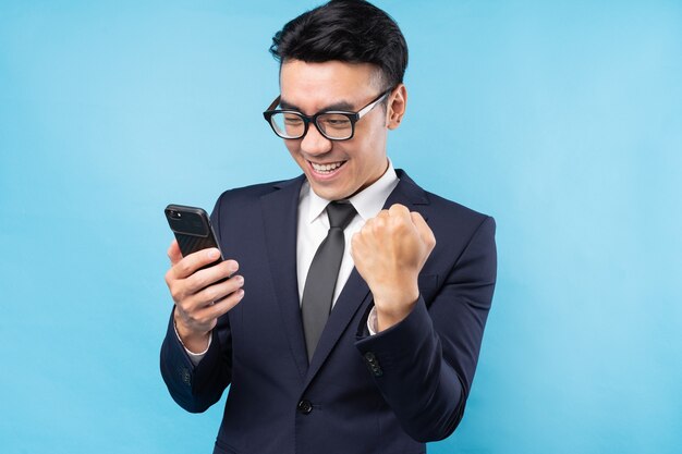 Asian businessman wearing suit using smartphone and feel victory