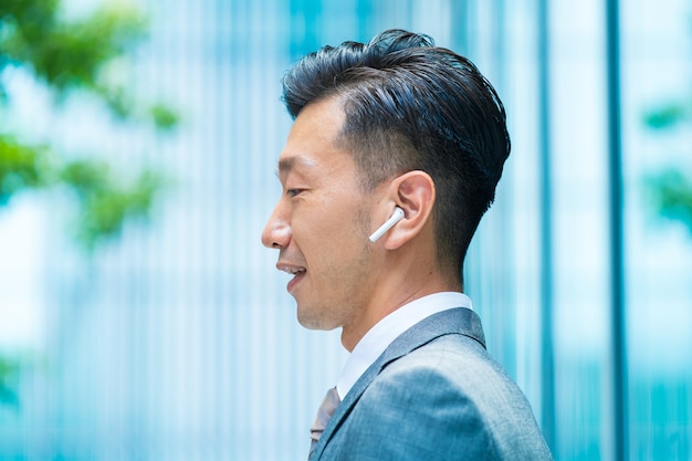 흰색 무선 이어폰을 착용하는 아시아 사업가