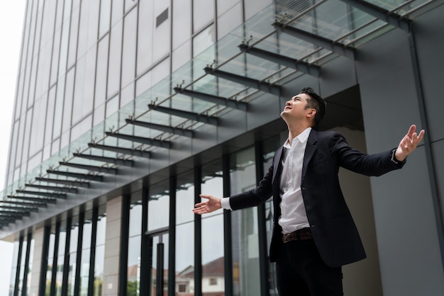 Asian Businessman with arms up celebrating victory in urban public spaces outside Concept Freedom and Successful