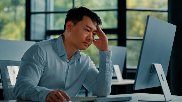 職場でオンラインで働くアジアのビジネスマンが困難な仕事に遭遇し、ビジネスの失敗に遭遇した