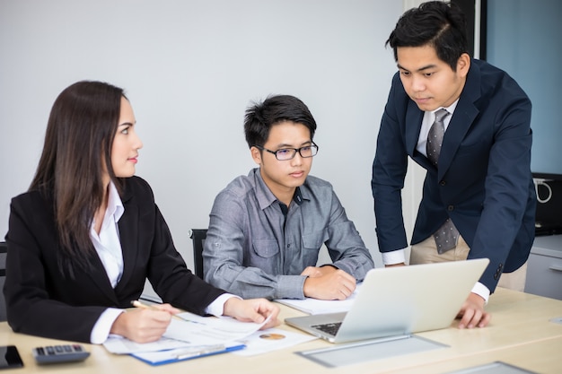 Asian businessmen and group using notebook for business partners discussing documents and ideas at meeting and business women smiling happy for working