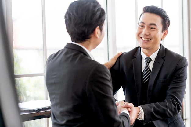 Asian businessmen handshake for the teamwork of business mergers and acquisitions for successful negotiation Two businessmen shake hands with partners to celebrate a partnership and business deals