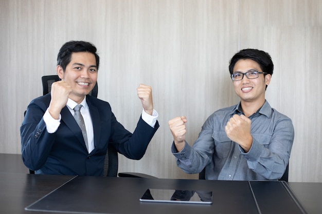 Asian businessmen success and winning concept - happy team with raised up hands celebrating the breakthrough and achievements