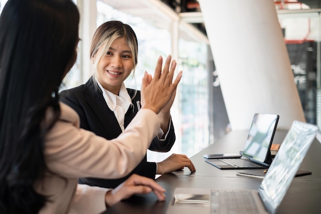 写真 アジアの実業家と彼女のパートナーは、チームビルディングプロジェクトの成功を祝い、お互いにハイタッチをします