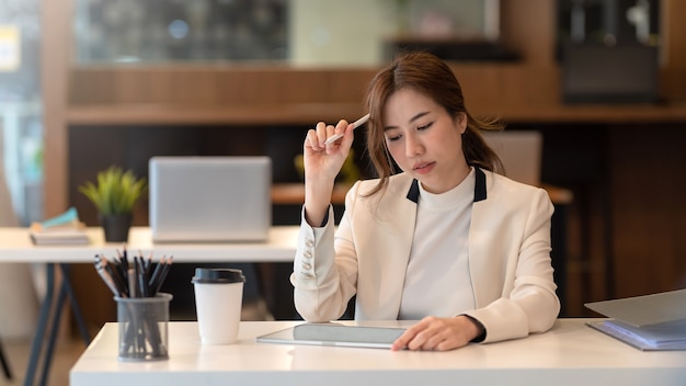 La donna d'affari asiatica è stanca annoiata con lo stesso lavoro ripetitivo usando un tablet in ufficio.