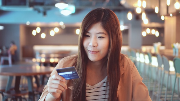 Asian businesswoman in casual suit using the credit card with computer for online shopping