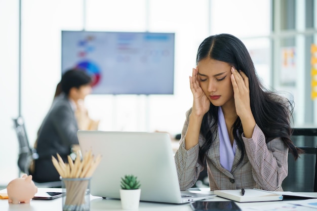 Donna d'affari asiatica che si sente stressata e mal di testa dopo aver lavorato a lungo concetto di sindrome da ufficio