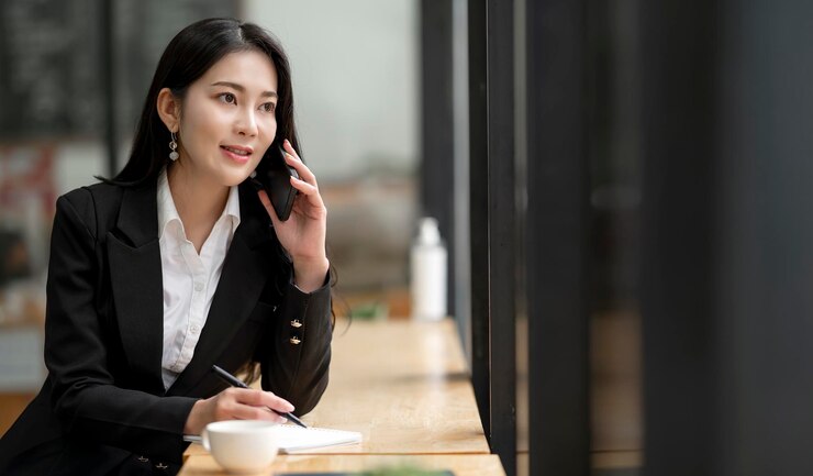 Photo 穿著正式西裝的亞洲女商人在辦公室,在使用智能手機和工作時開心而愉快
