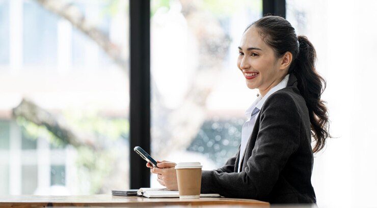 Photo スマートフォンを使用し ⁇ 働いている間 ⁇ オフィスに座っている正式なスーツを着たアジア人女性ビジネスマン ⁇ 
