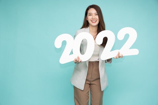 녹색 배경에 고립 된 2022 번호를 들고 아시아 사업가