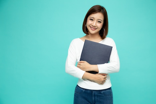 Asian businesswoman holding documents files standing over green wall