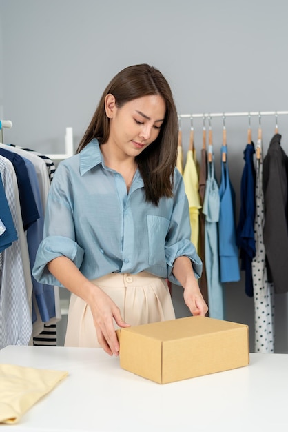 Asian businesswoman packing cloths in box for delivery. Online selling and e-commerce business.