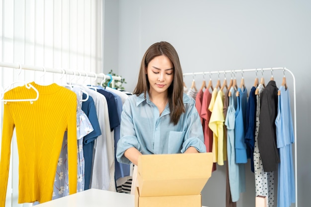 Asian businesswoman packing cloths in box for delivery. Online selling and e-commerce business.