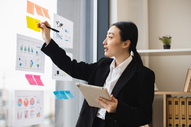 Photo asian businesswoman presenting analysis with graphics and tablet