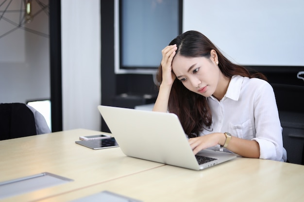 Donna di affari asiatica seriamente sul lavoro fatto fino al mal di testa