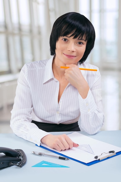 Asian businesswoman sitting at table and looking at camera