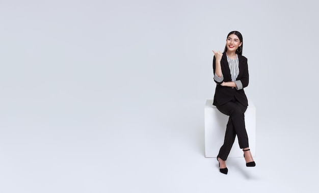 asian businesswoman smile in formal suit sitting on chair and points her hands presented