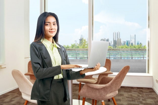 Asian businesswoman standing while using a laptop working from home