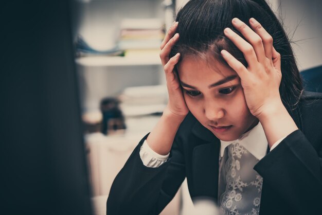 Asian businesswoman stress from hard workThai worker woman working in the officeDark tone