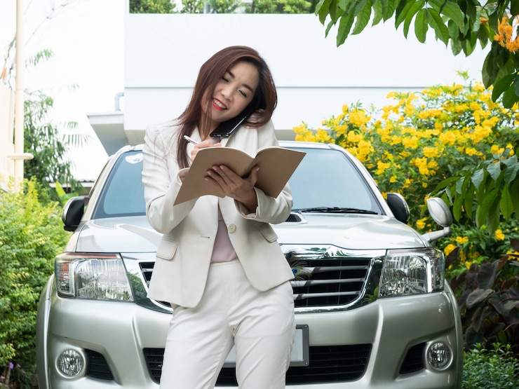 https://img.freepik.com/premium-photo/asian-businesswoman-talking-mobile-phone-making-notes-against-car_33741-298.jpg?w=740