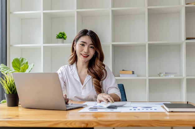 Asian businesswoman typing laptop in her private office, she is using her laptop to type, send business messages with a partner, she uses internet messenger. Asian business woman concept.