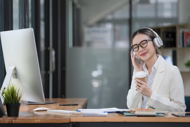 an asian businesswoman using a computer and listening to music while working