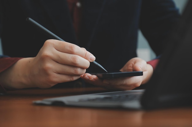 Asian Businesswoman Using laptop computer and working at office with calculator document on desk doing planning analyzing the financial report business plan investment finance analysis concept