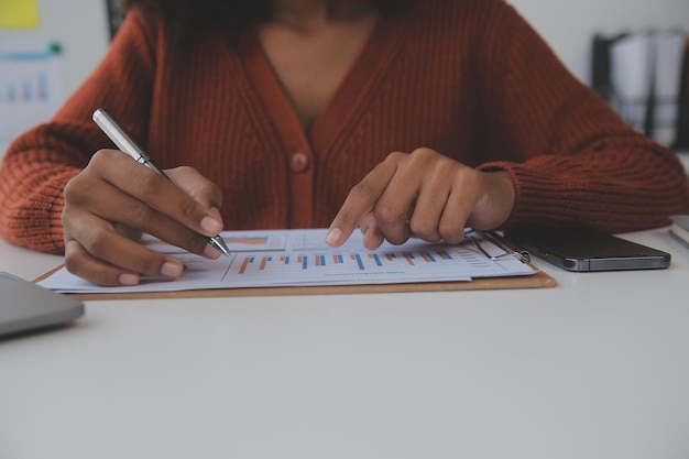 Asian Businesswoman Using laptop computer and working at office with calculator document on desk doing planning analyzing the financial report business plan investment finance analysis concept