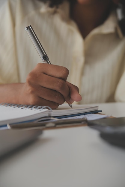 Asian Businesswoman Using laptop computer and working at office with calculator document on desk doing planning analyzing the financial report business plan investment finance analysis concept